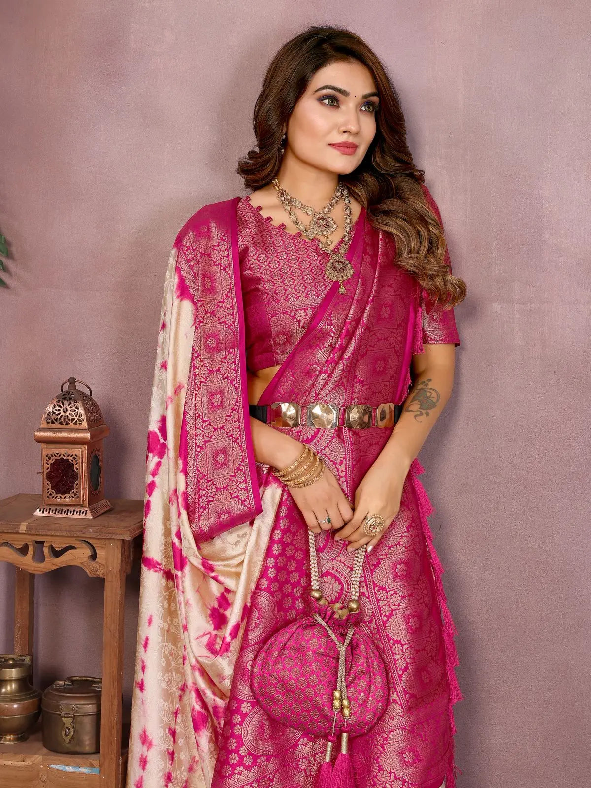 Woman wearing a pink saree with a matching blouse against a purple background